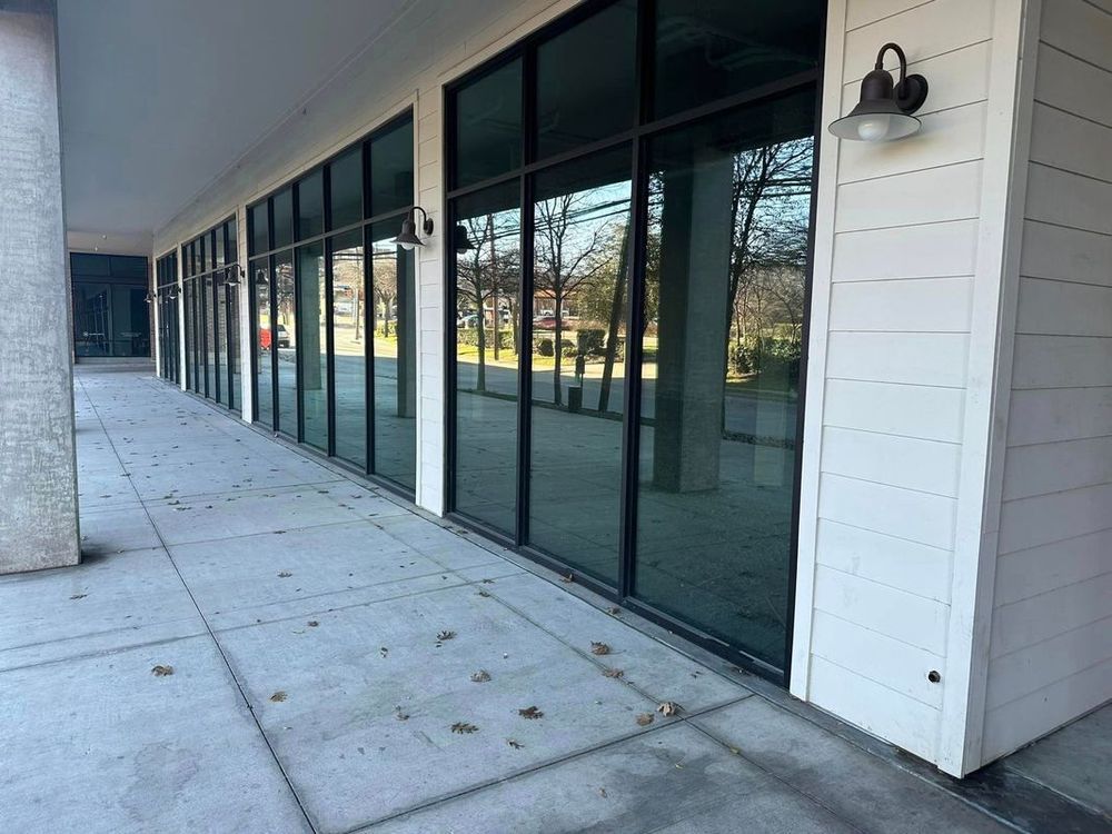Storefront walkway with large glass windows and white siding under an overhang