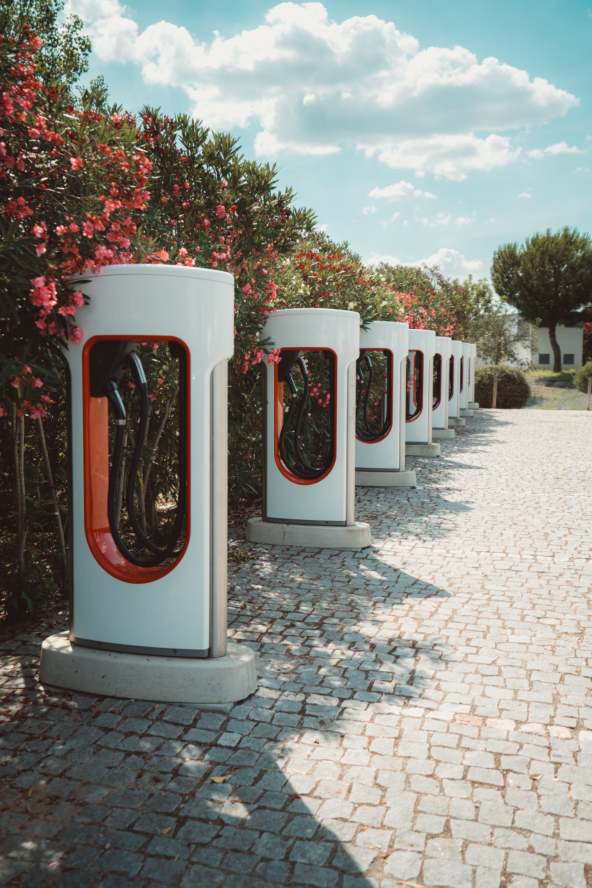 A row of electric car charging stations on a cobblestone road.