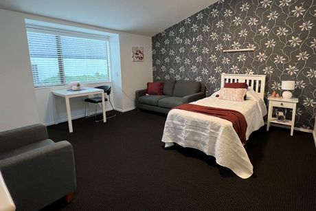 A bedroom with a bed , couch , desk and chair.