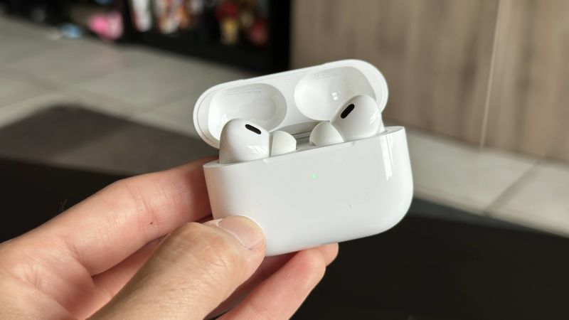 Uma pessoa está segurando um par de AirPods brancos na mão.