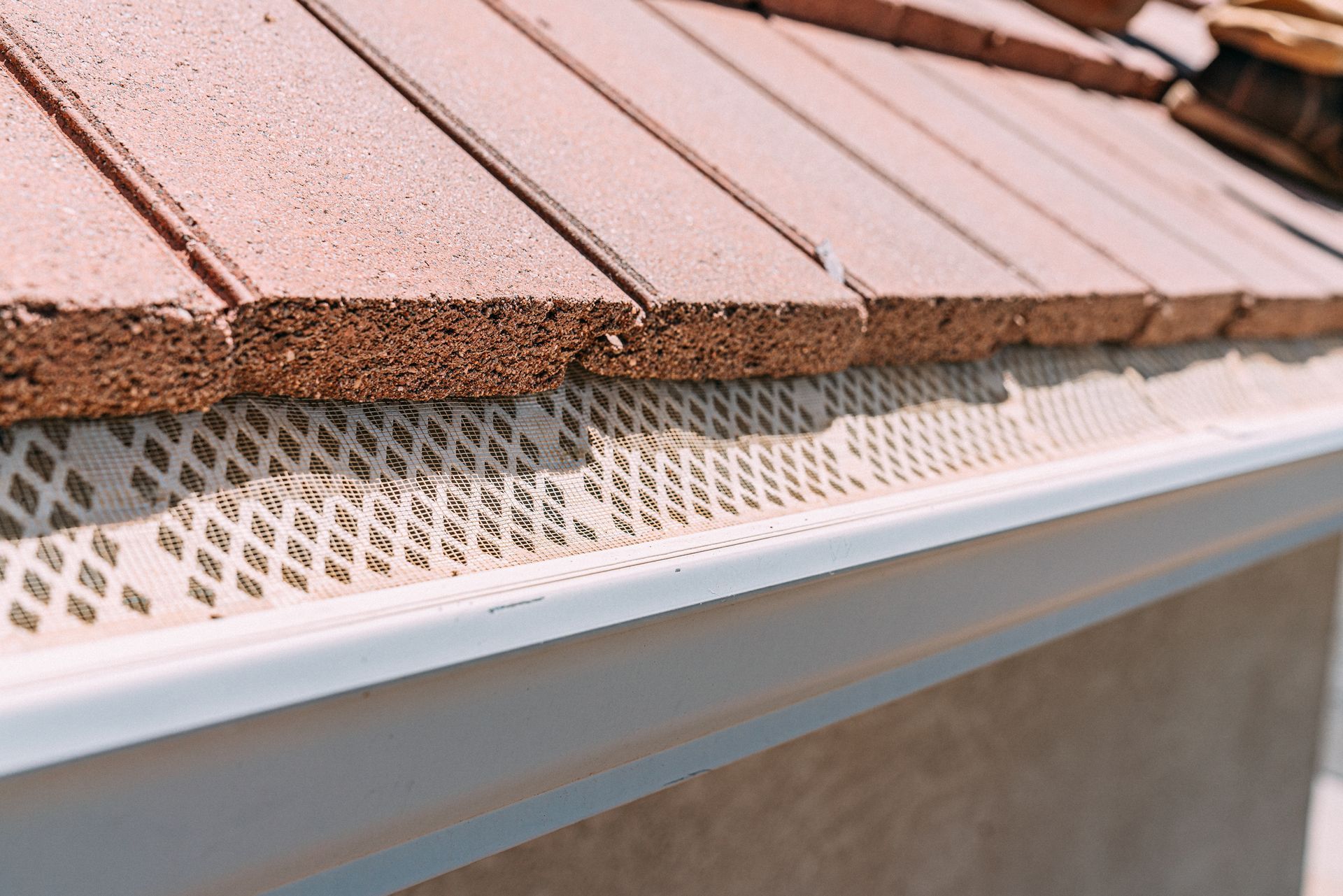 A person is installing a white gutter on a roof.