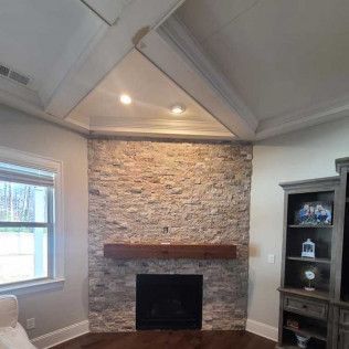 An indoor stone and concrete fireplace with mantel in Rock Hill, SC with Carolina Mega Concrete LLC