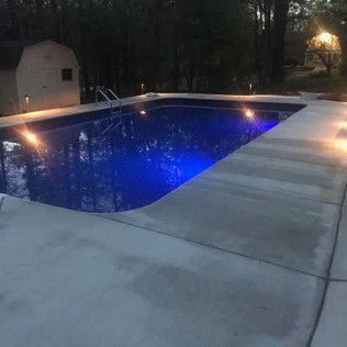 An after of the finished concrete pool deck lit up at night in Rock Hill, SC by Carolina Mega Concrete LLC