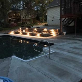 An after of the finished concrete pool deck lit up at night in Rock Hill, SC by Carolina Mega Concrete LLC