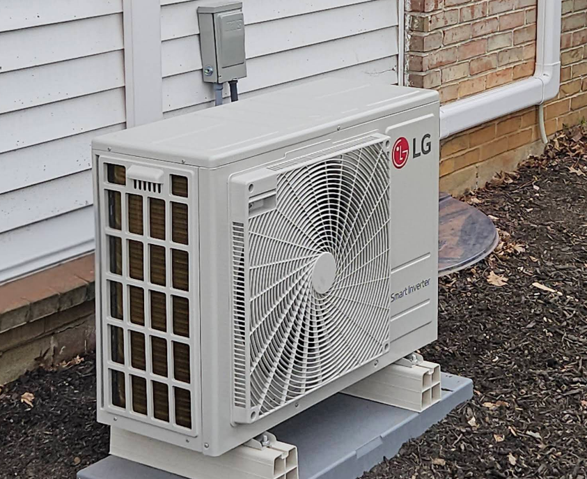 LG air conditioner unit mounted on concrete blocks outside a building.