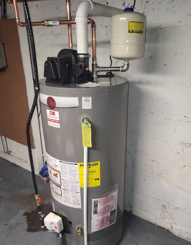 Gray water heater in a basement with copper pipes and an expansion tank.
