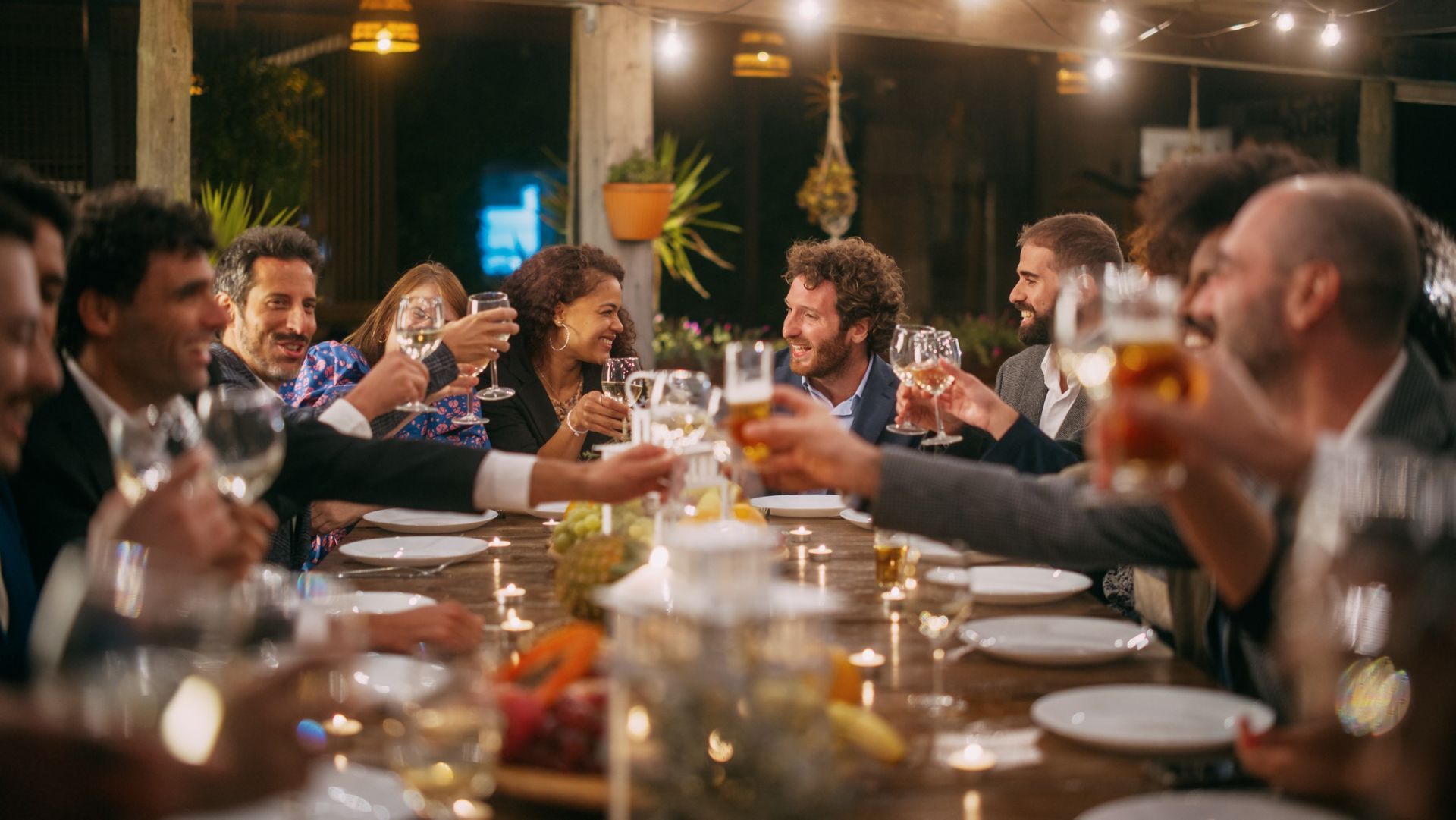 group of people clinking glasses at large party