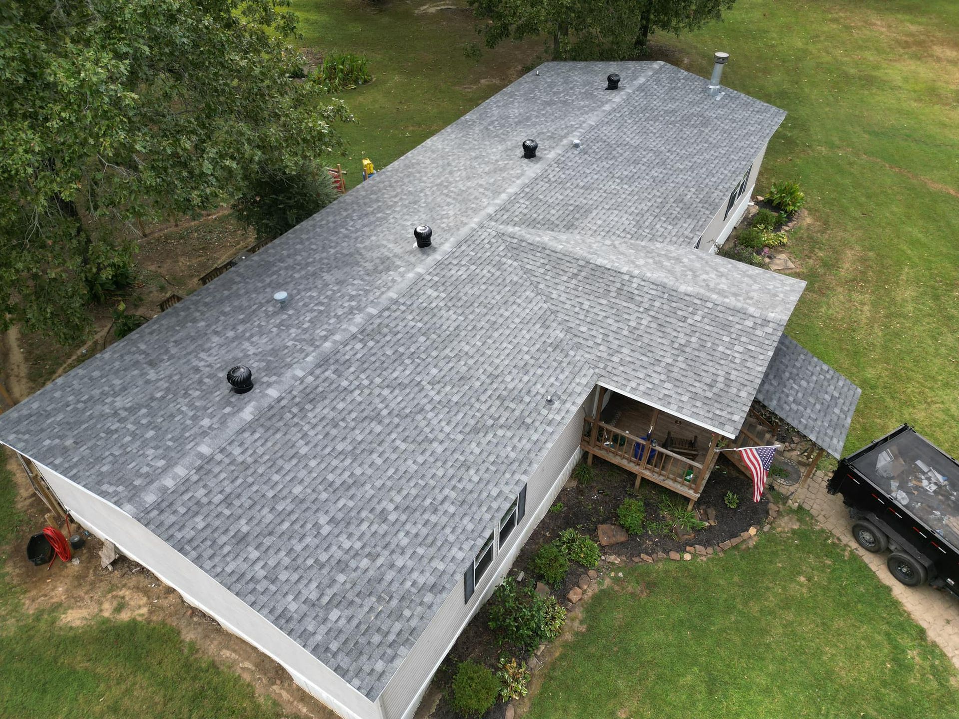 Aerial view of a house with a gray shingle roof in a grassy yard.