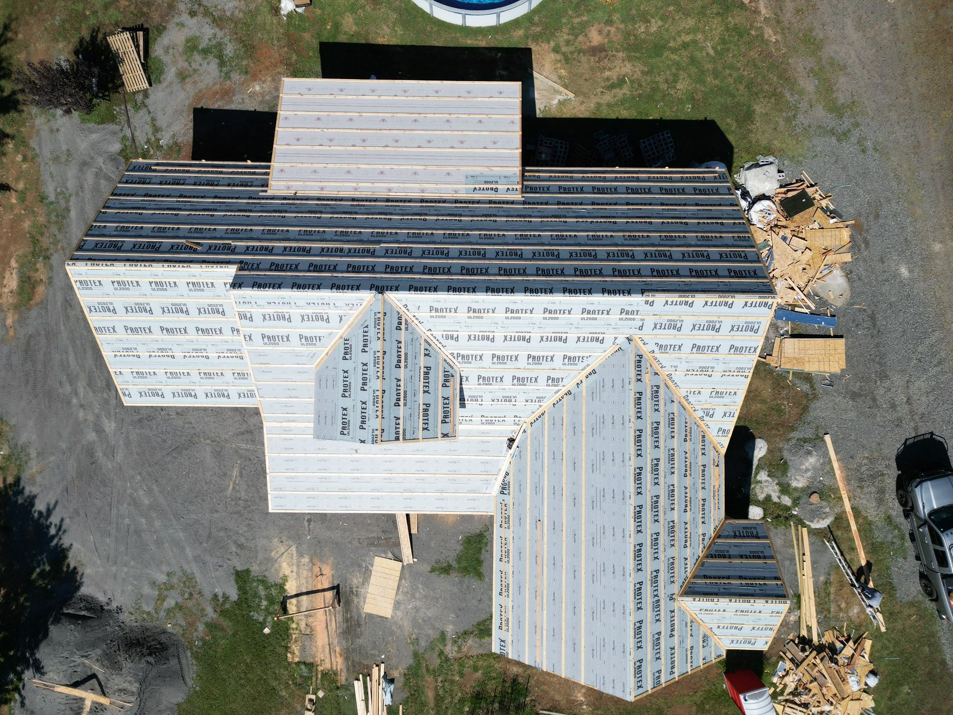 Overhead view of a house under construction; exposed roof beams and sheathing.