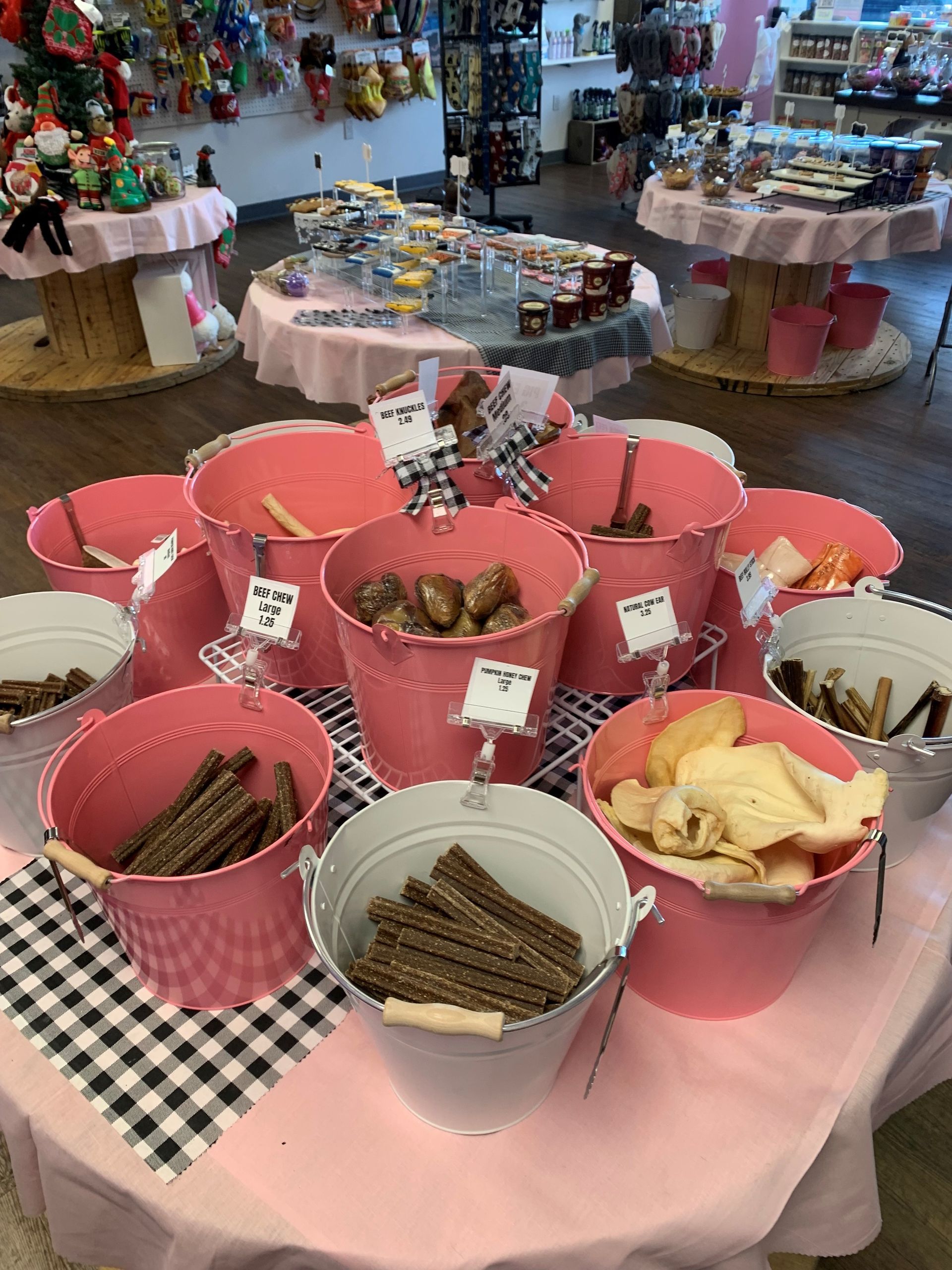 A table with buckets of dog treats on it in a store.