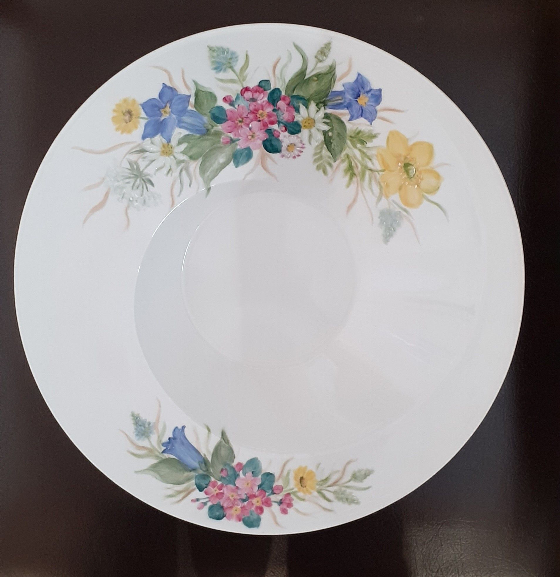 Ciotola bianca con motivo floreale di fiori rosa, blu e gialli lungo il bordo.