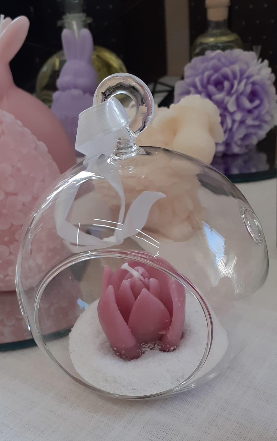 Terrario a sfera in vetro con candela a forma di loto rosa, decorato con nastro bianco.