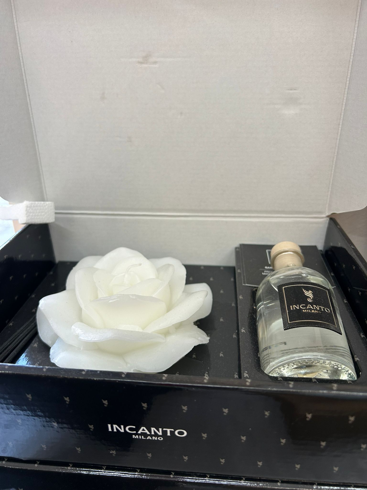 Scatola regalo con un oggetto a forma di rosa bianca e una boccetta di profumo.