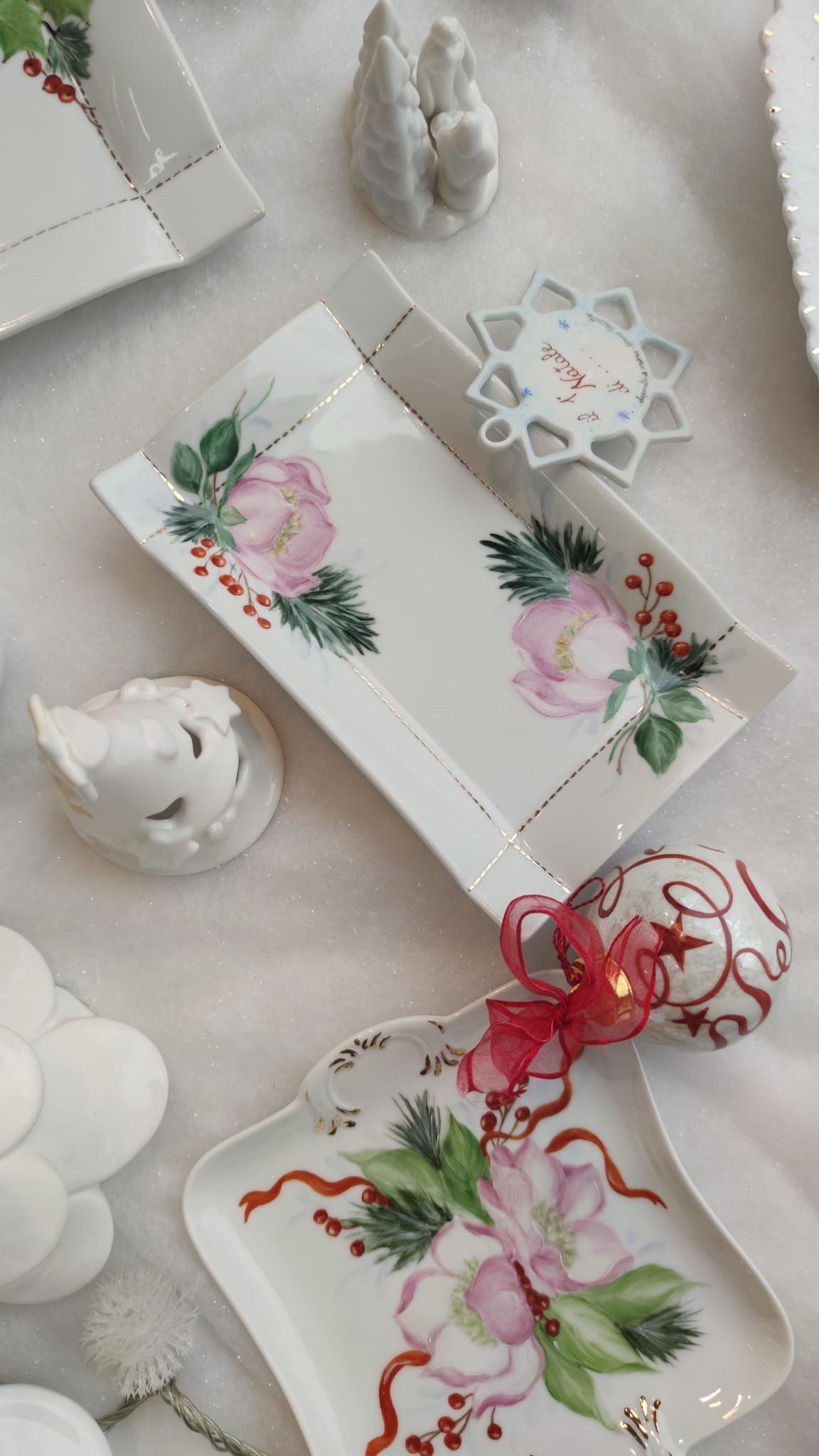 Piatti da portata dipinti a fiori con decorazioni natalizie su una superficie bianca.