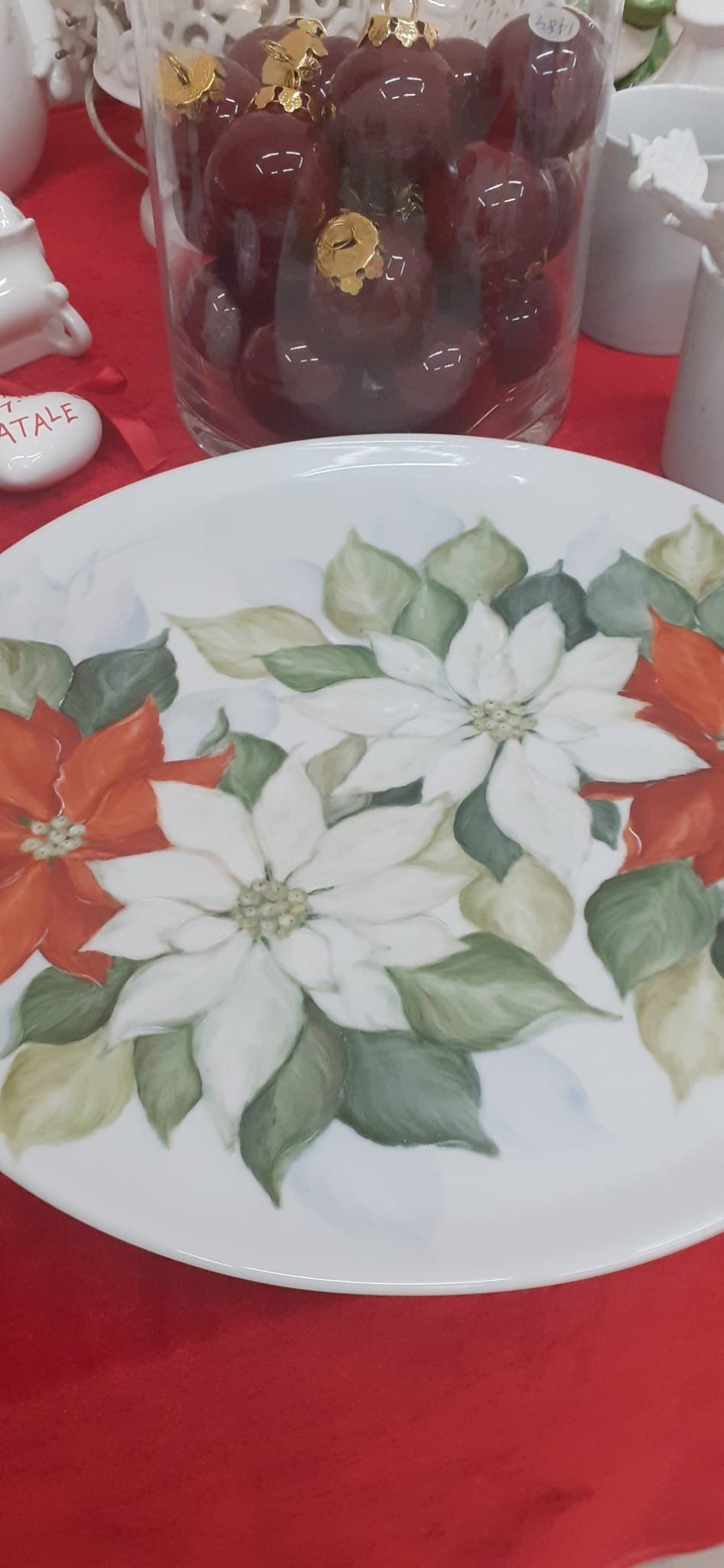 Piatto bianco con motivo a stella di Natale, tovaglia rossa, uva in un bicchiere.