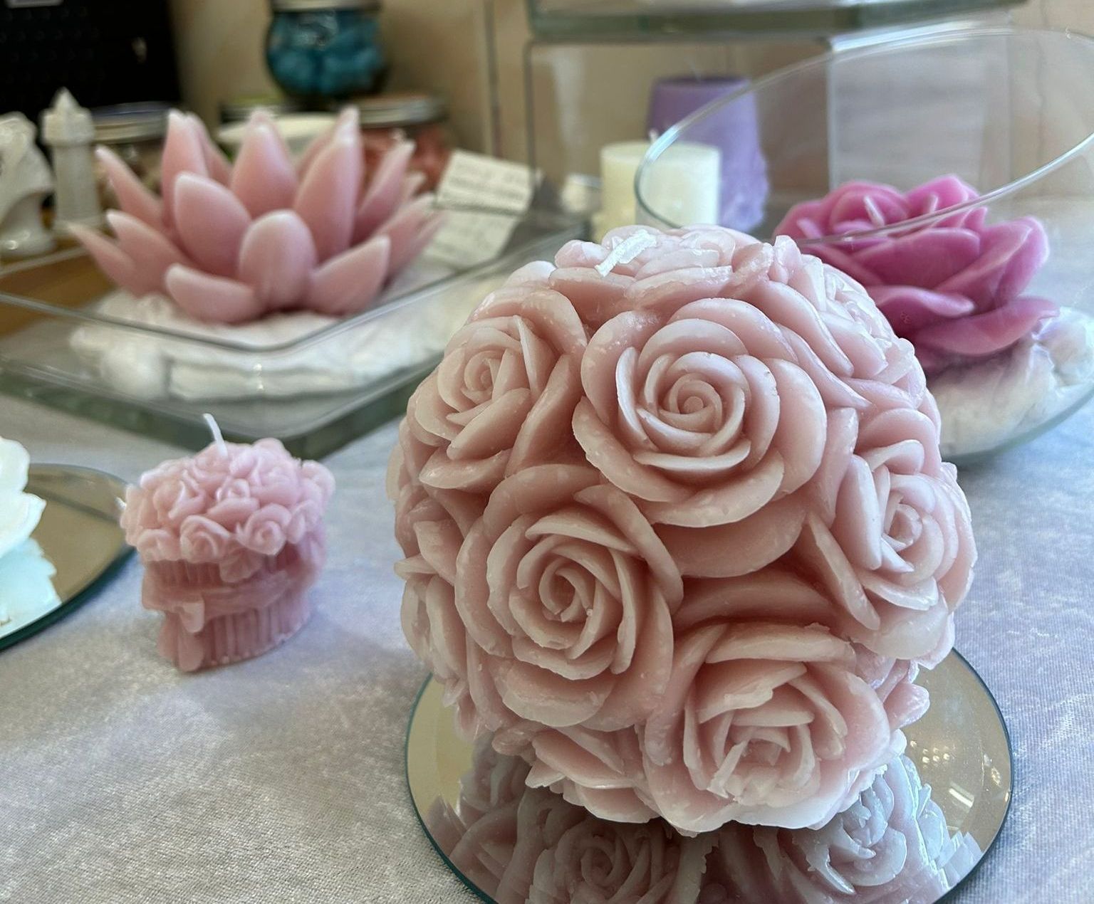 Candele rosa a forma di rosa su superfici a specchio, che mettono in risalto dettagli intricati.