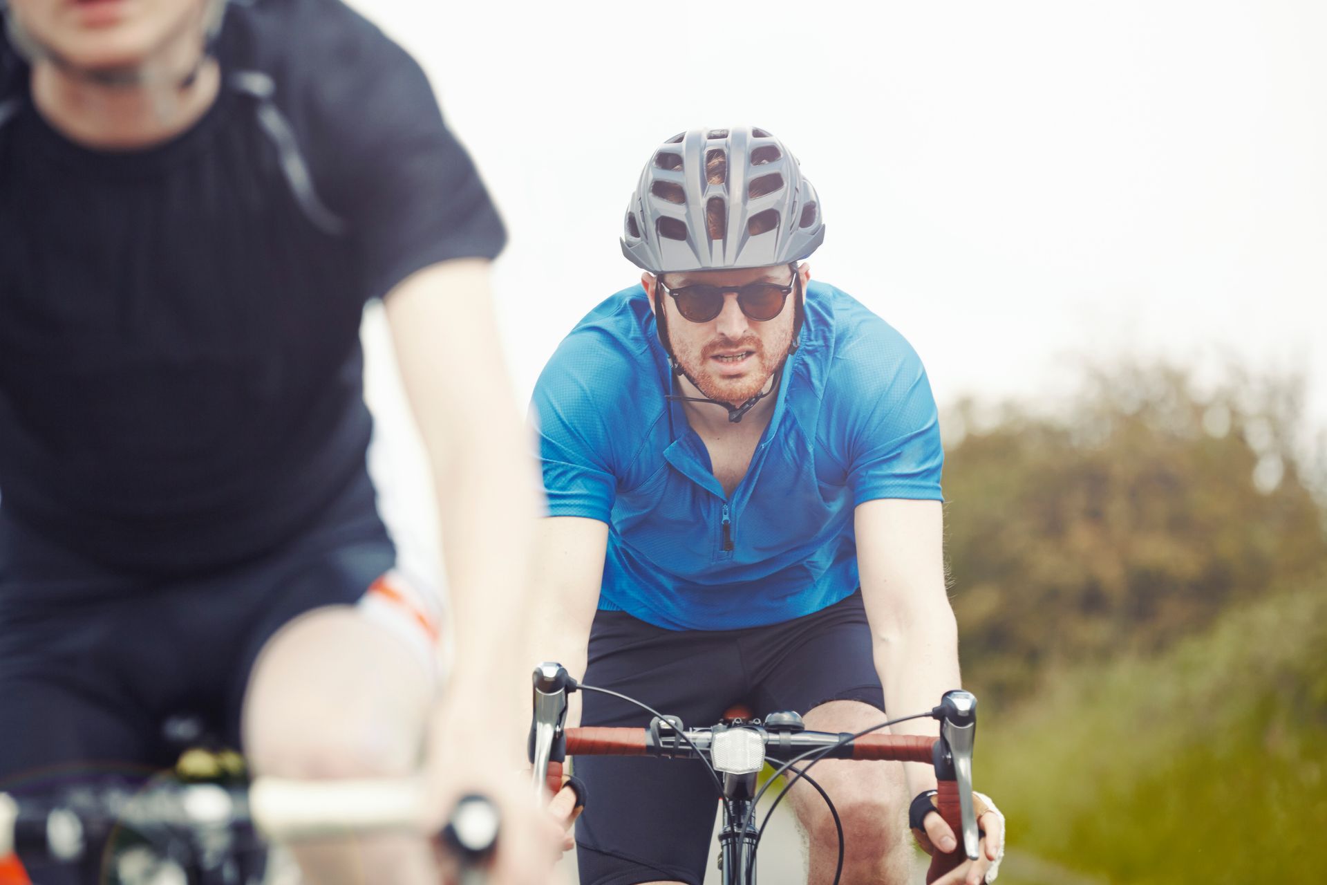 Cyclists riding on a road, with a man in a blue jersey and helmet in focus