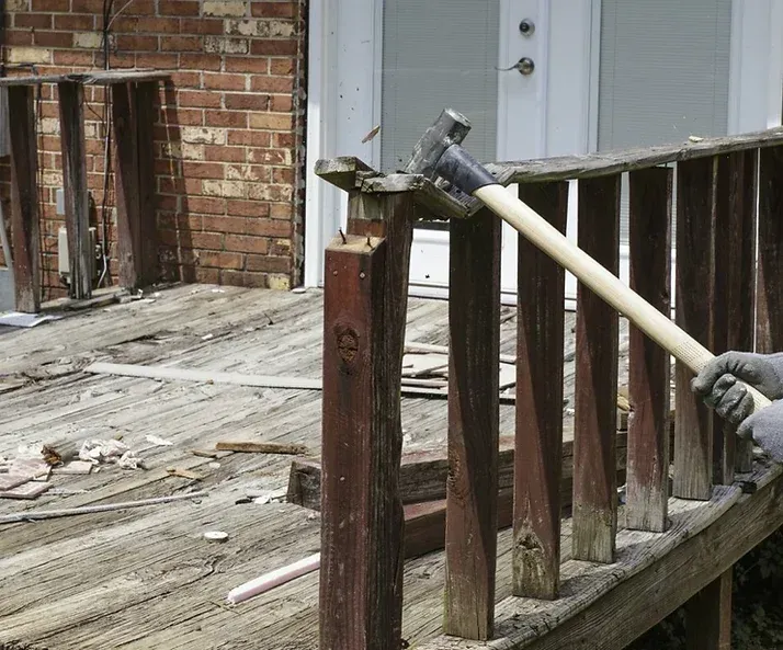 A person is holding a hammer on a wooden deck