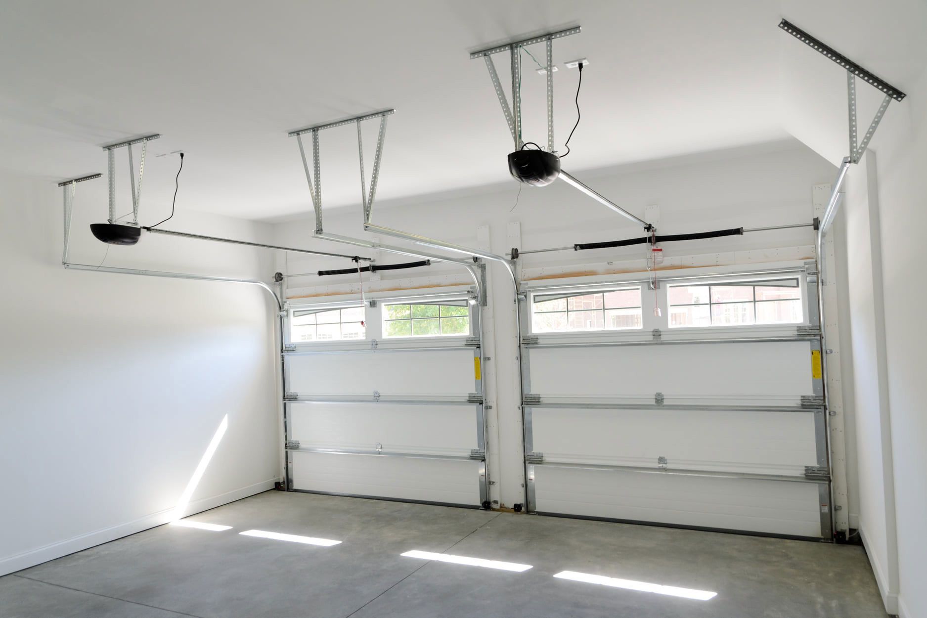 An empty garage with two garage doors and a ceiling fan