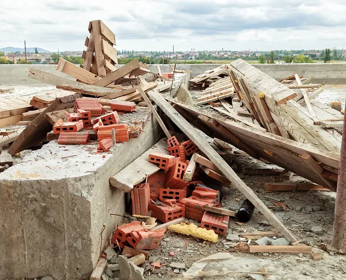 A pile of bricks and wood is laying on the ground.