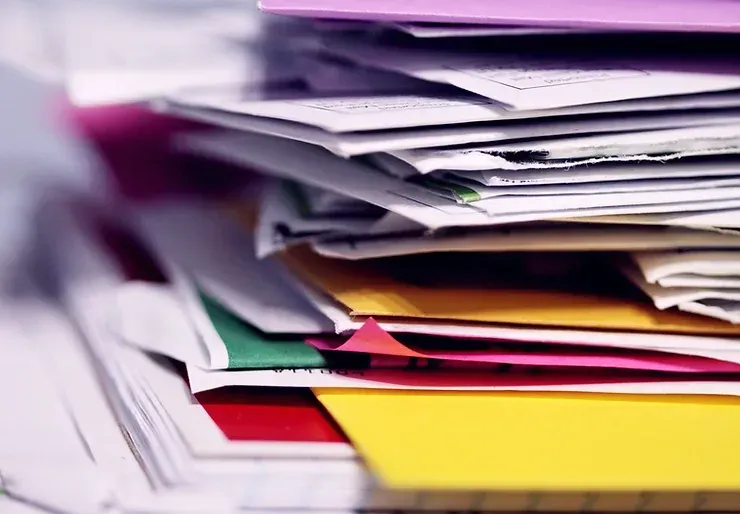 A stack of colorful envelopes and papers on a table