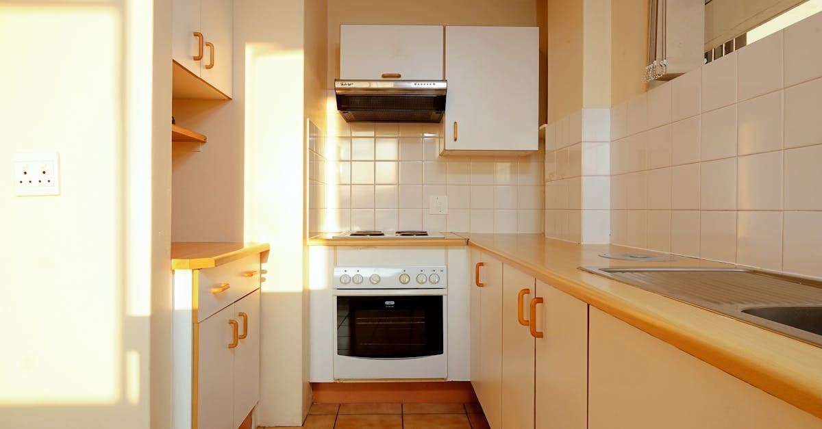 An empty kitchen with white cabinets and a stove top oven