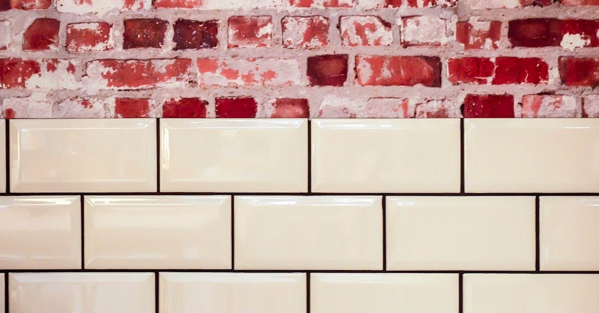 A close up of a brick wall with white tiles on it.