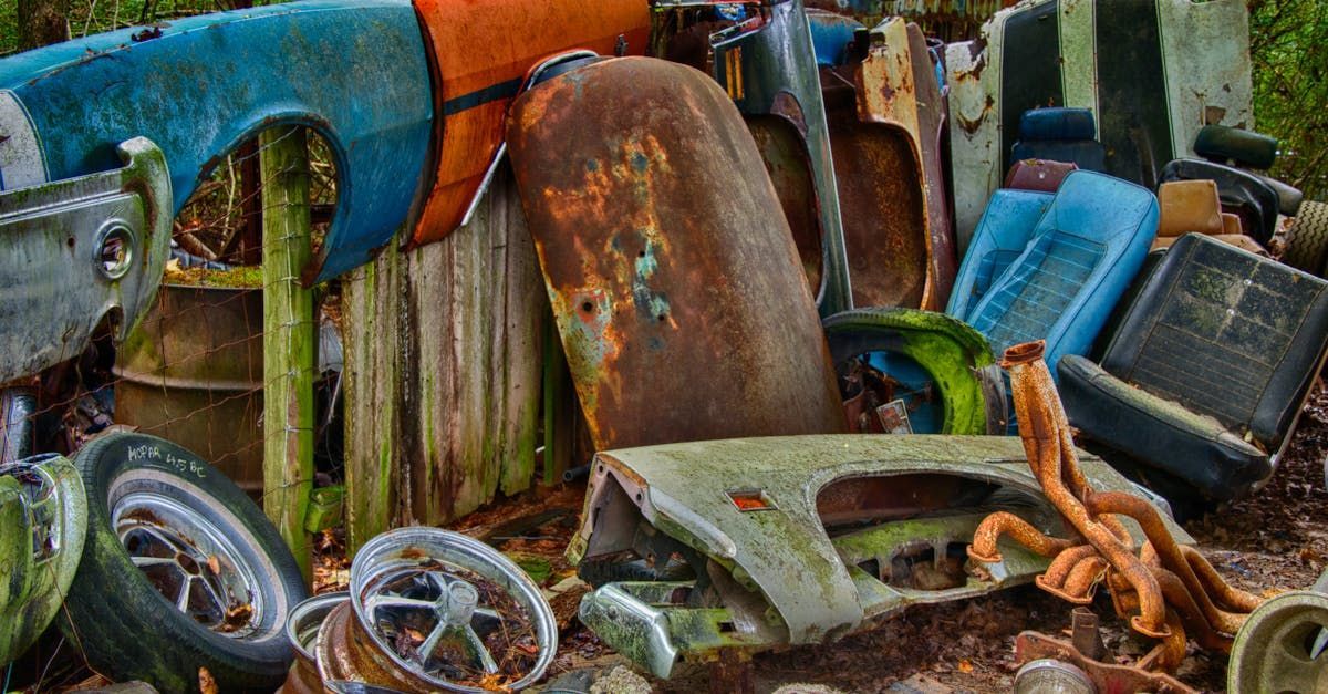 A pile of rusty car parts and tires on the ground.