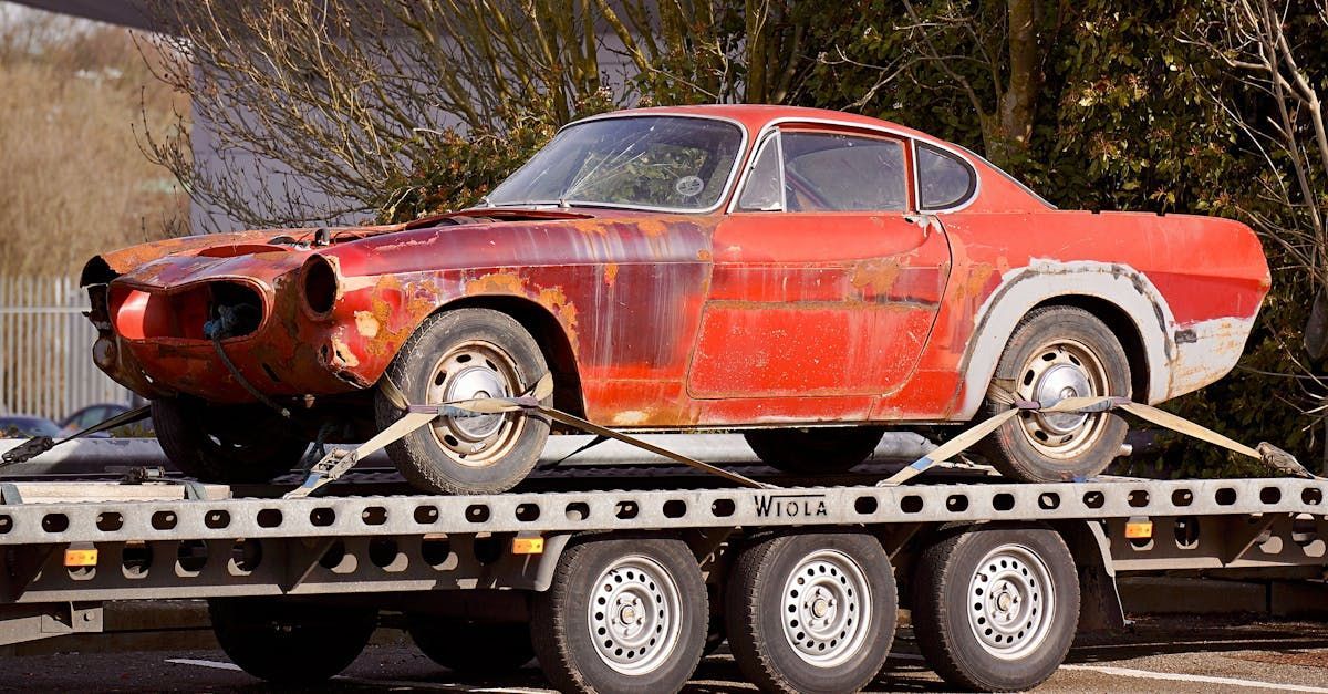 A red car is sitting on top of a tow truck.