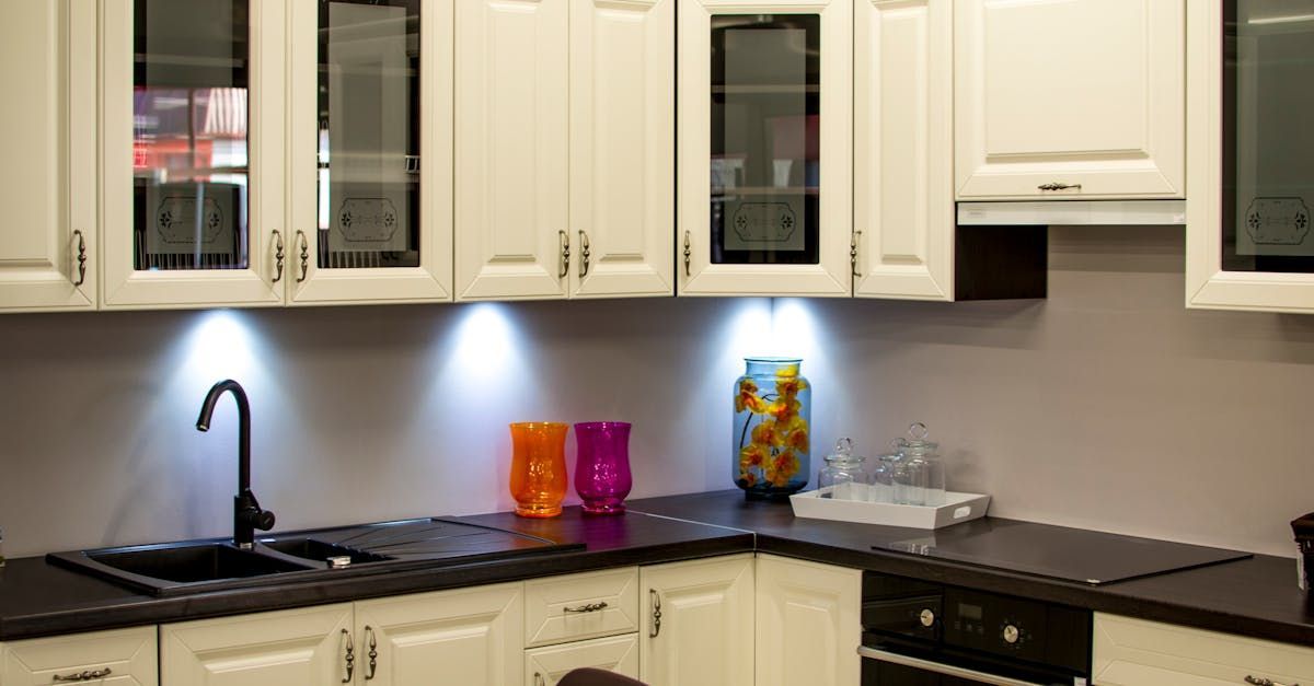 A kitchen with white cabinets and black counter tops