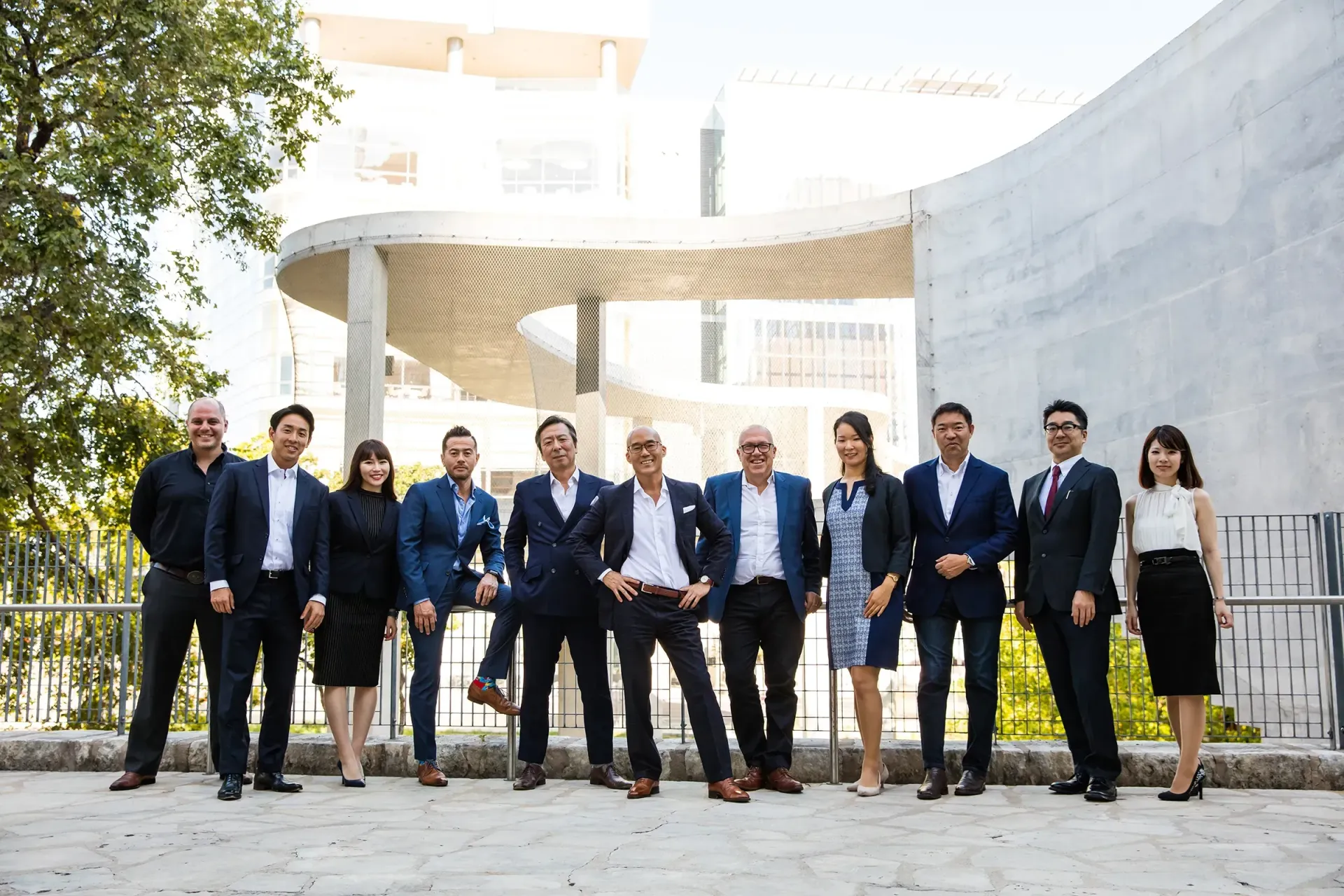 A group of business people are posing for a picture in front of a building.