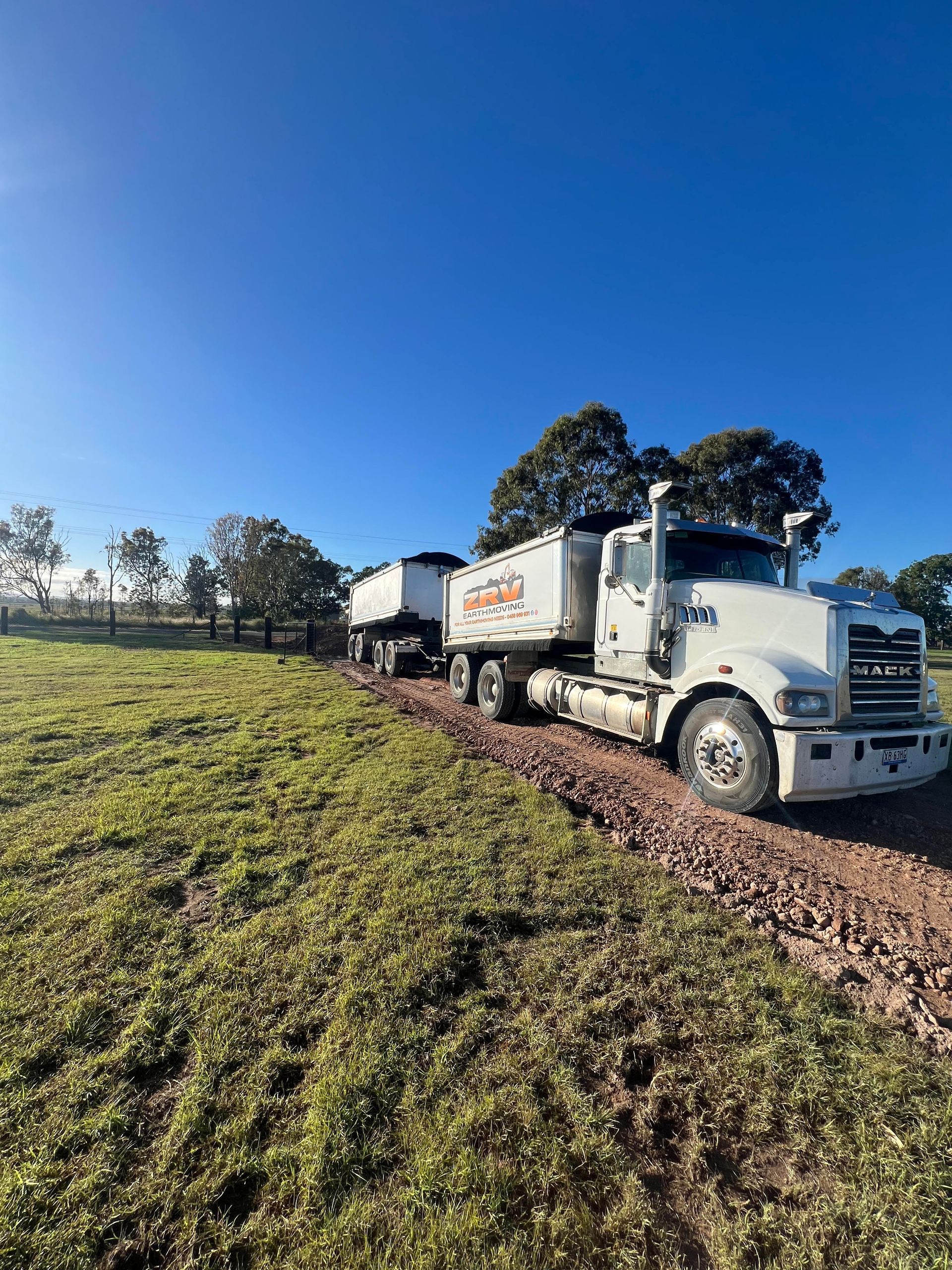 A truck is carrying a small excavator on a trailer.