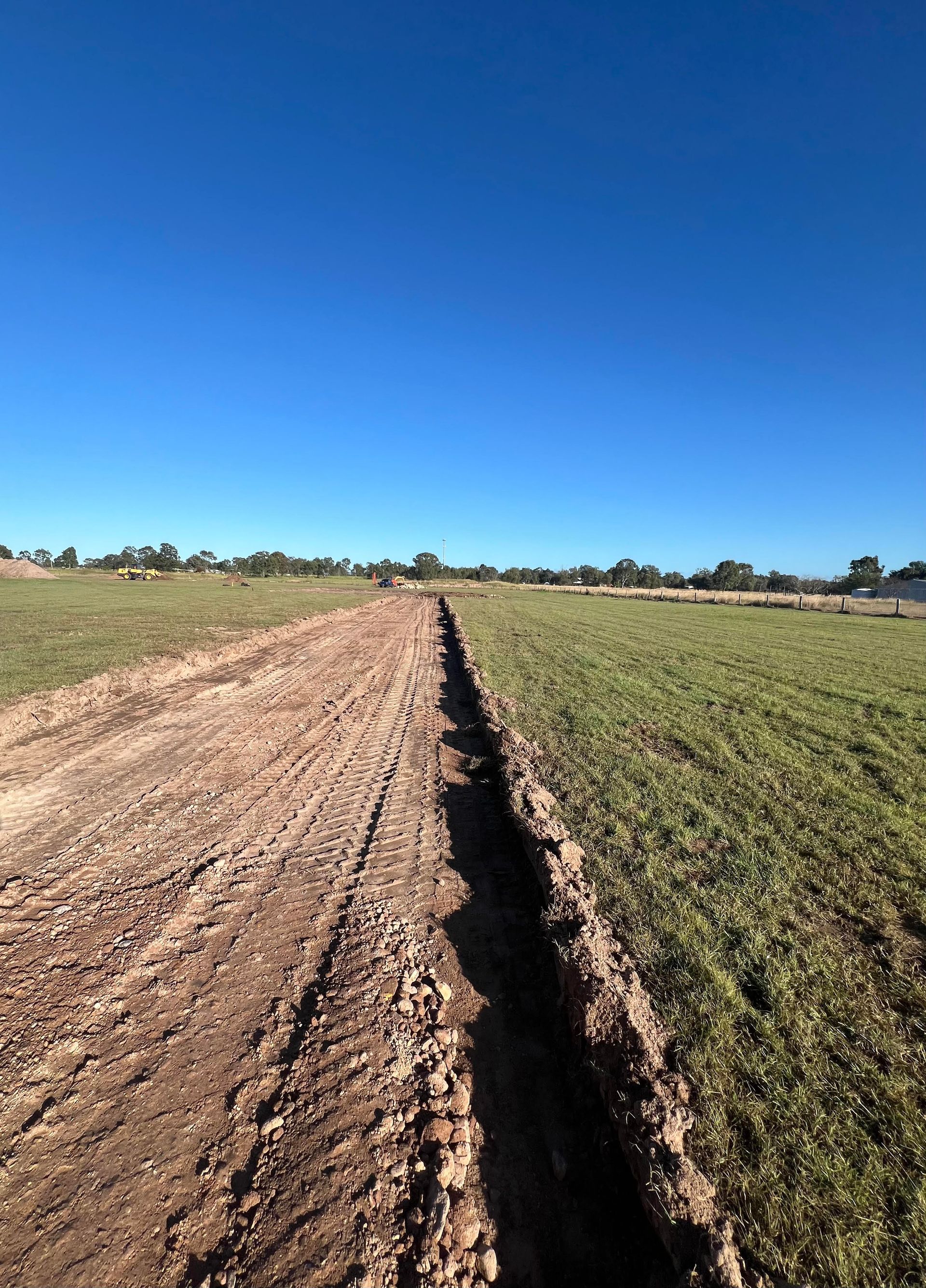 A pipe is being installed in the dirt in a field.