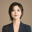 Woman with dark hair in a blue blazer poses for a professional portrait against a neutral background.