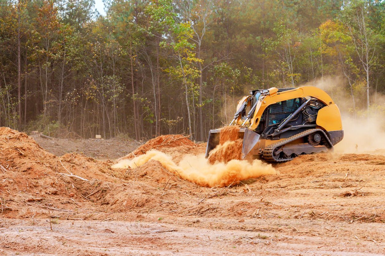 Yellow bulldozer pushing dirt through a muddy construction site, throwing up dust