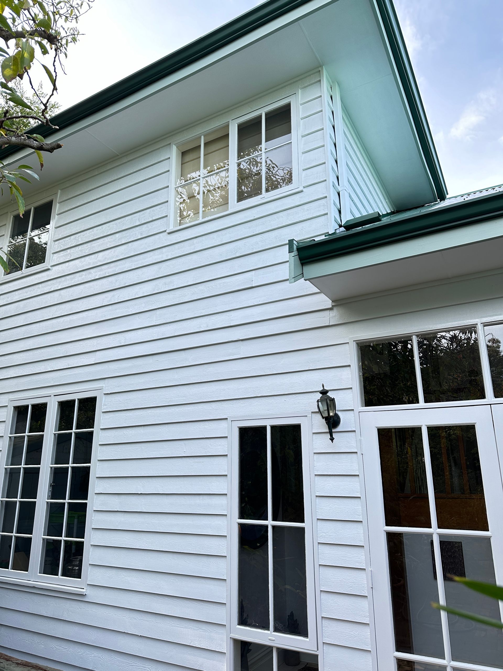 White wooden house with multiple windows and a green roof.