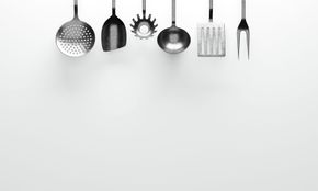 Kitchen utensils hanging on hooks against a white wall