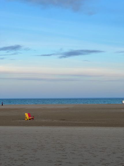 Empty beach with a red and yellow chair under a blue sky at dusk