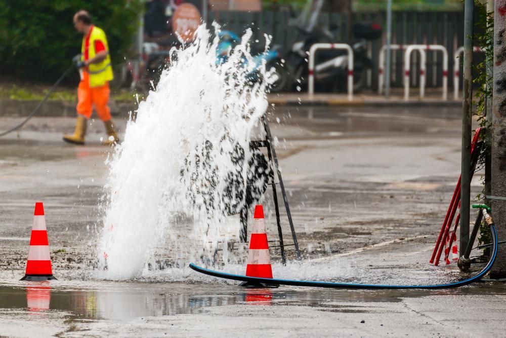 A Man is Spraying Water From a Pipe in a Puddle — Gold Coast Leak Detection in Mudgeeraba, QLD 