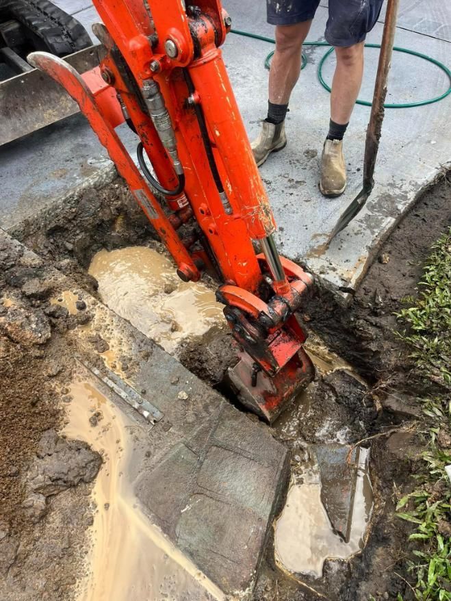 A Man is Using an Excavator to Dig a Hole in the Ground — Gold Coast Leak Detection in Mudgeeraba, QLD 