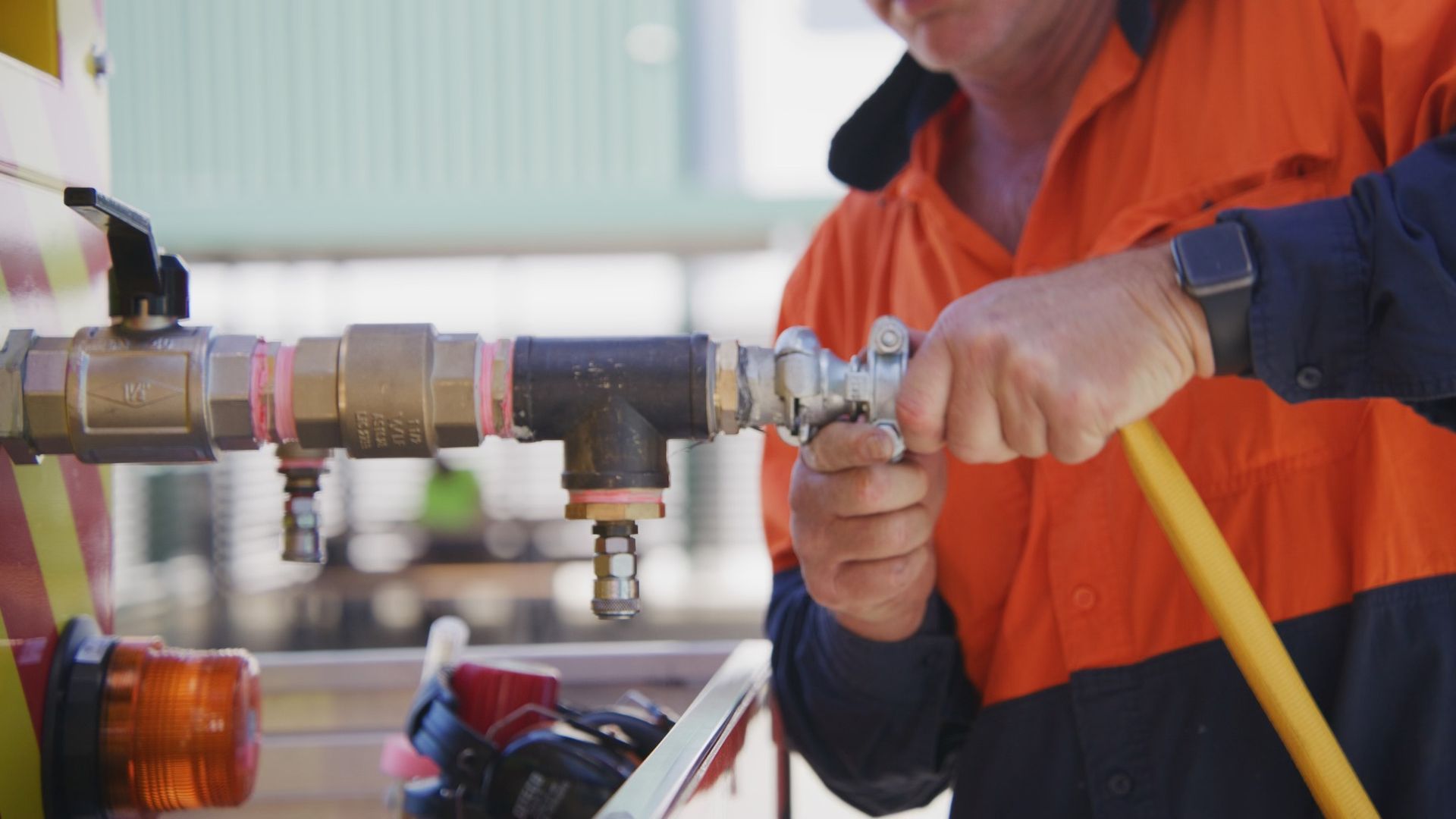 Worker in Orange Workwear Connects a Hose — Gold Coast Leak Detection in Yatala, QLD
