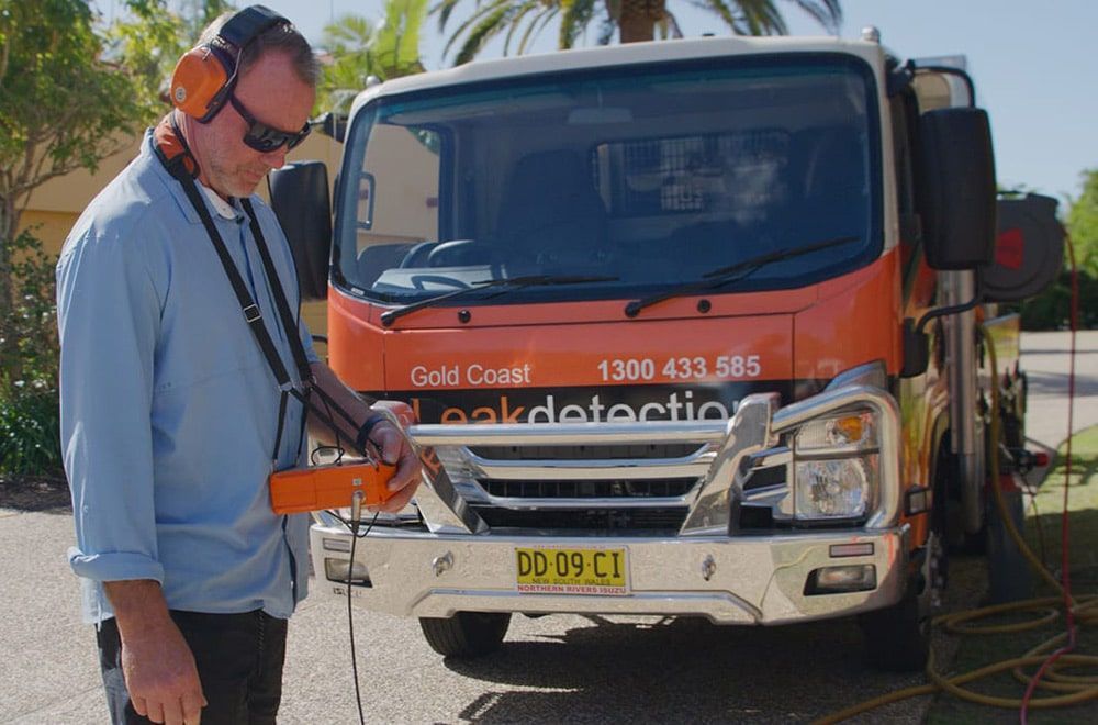 A Man Wearing Headphones is Standing in Front of a Truck — Gold Coast Leak Detection in Mudgeeraba, QLD