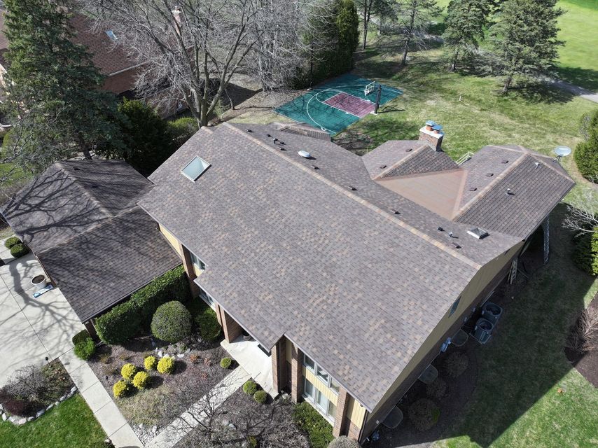An aerial view of a house with a basketball court in the backyard.