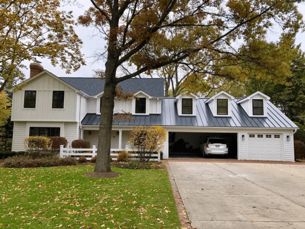 A white house with a blue roof and a car in the garage