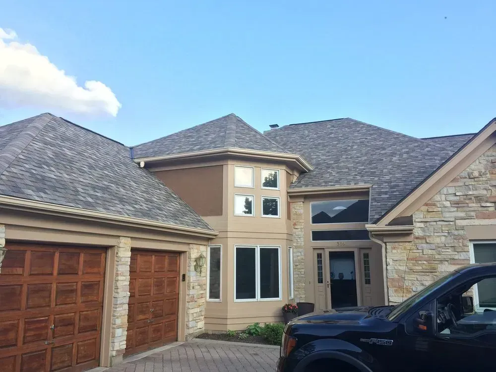 A black truck is parked in front of a large house.