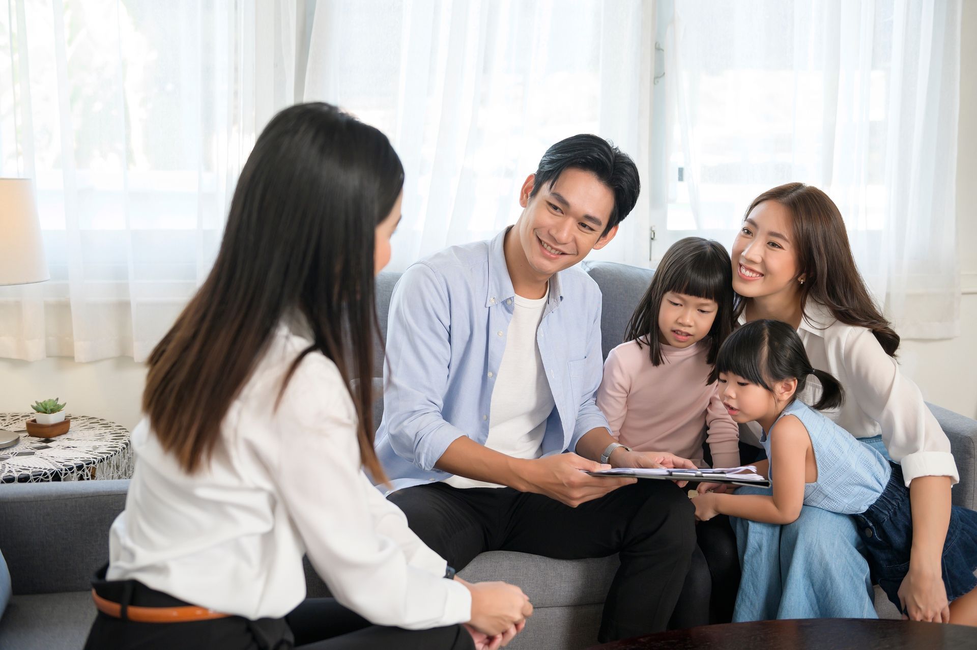 A family is sitting on a couch talking to a woman.