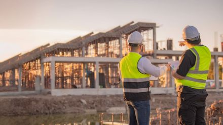 A group of people are sitting around a table with hard hats and blueprints.