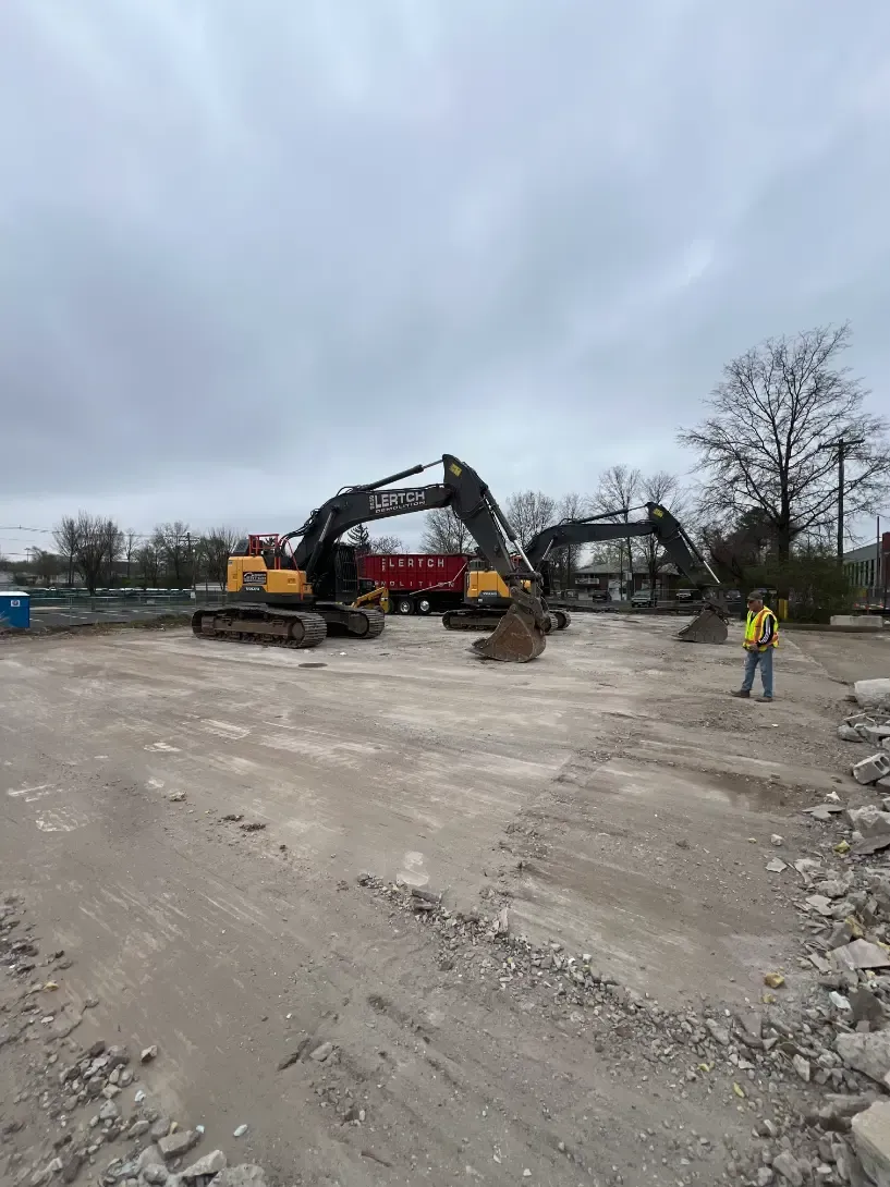 A couple of excavators are sitting in a dirt field.
