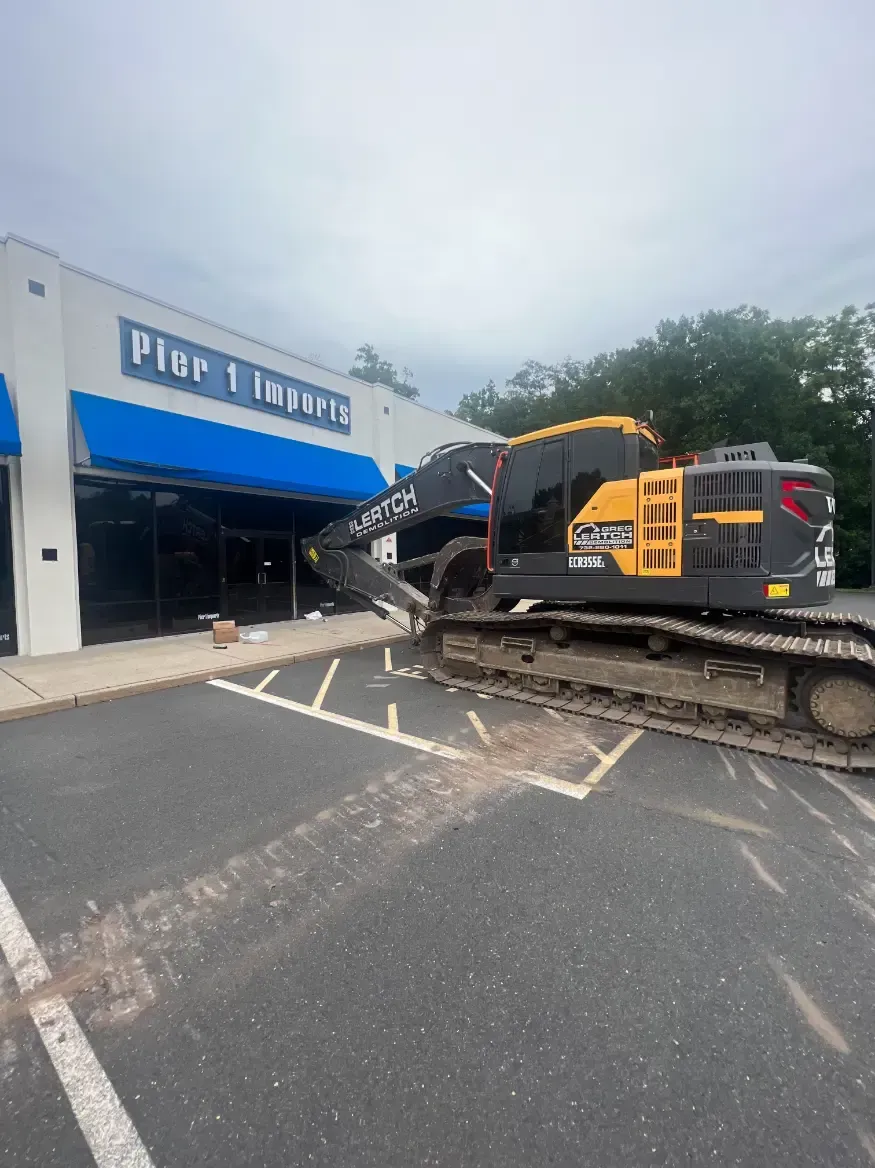 A large excavator is parked in front of a pier 1 imports building.