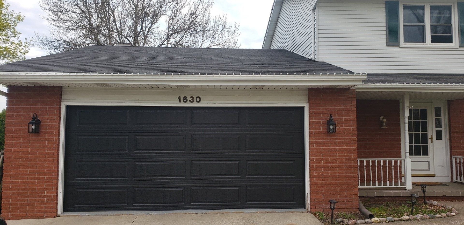 Brick house with black garage door and front porch, numbered 1830
